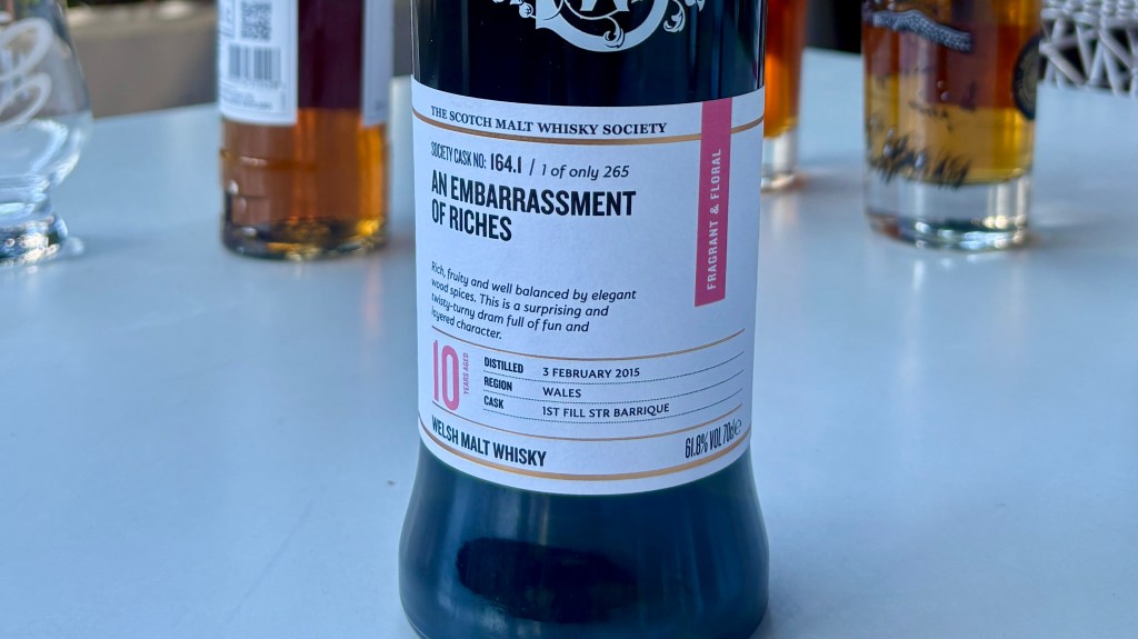 Bottle of Welsh malt whisky labeled 'An Embarrassment of Riches' with details about the distillation and tasting notes.