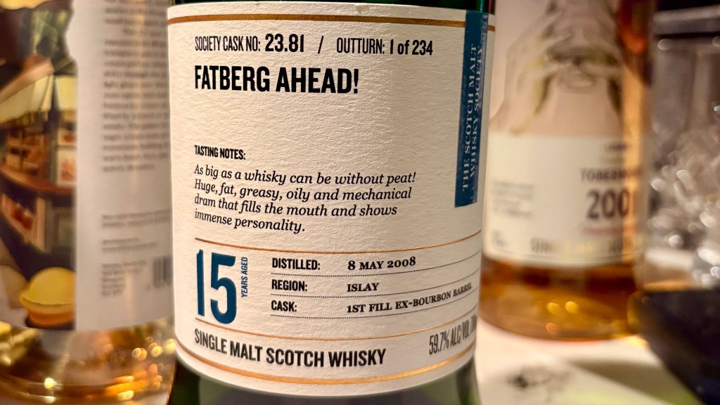 Close-up of a whisky bottle label featuring 'Fatberg Ahead!' with tasting notes, age statement of 15 years, and details about the distillation process and region.