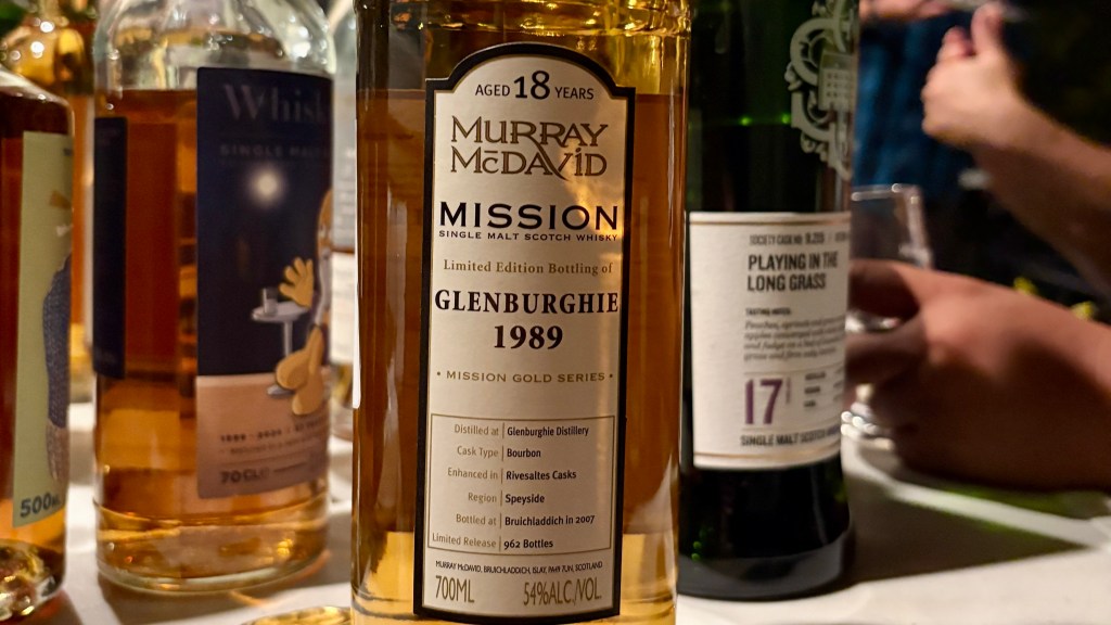Close-up of a bottle of Glenburgie 1989 single malt Scotch whisky, aged 18 years, part of the Murray McDavid Mission series, with other whisky bottles partially visible in the background.